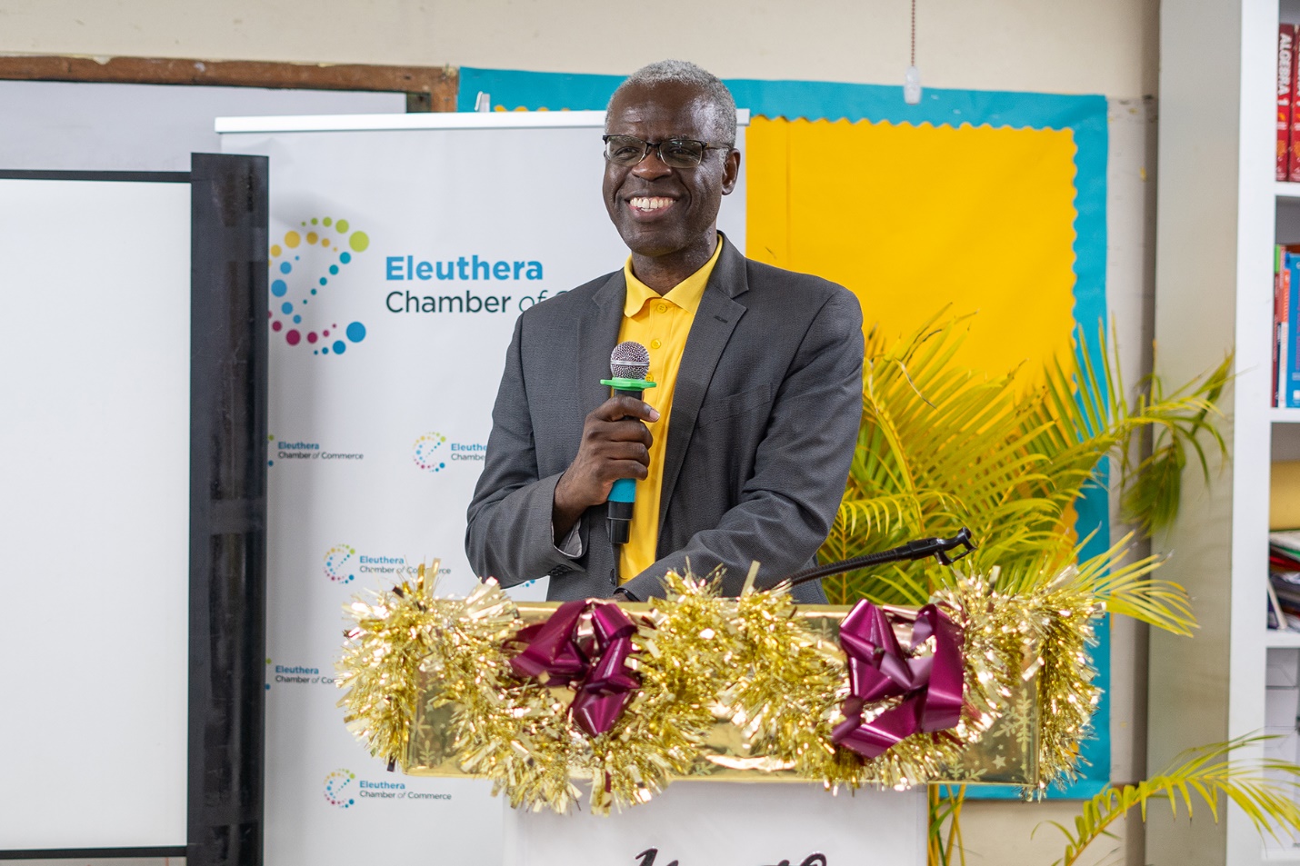 A person standing at a podium holding a microphone

Description automatically generated